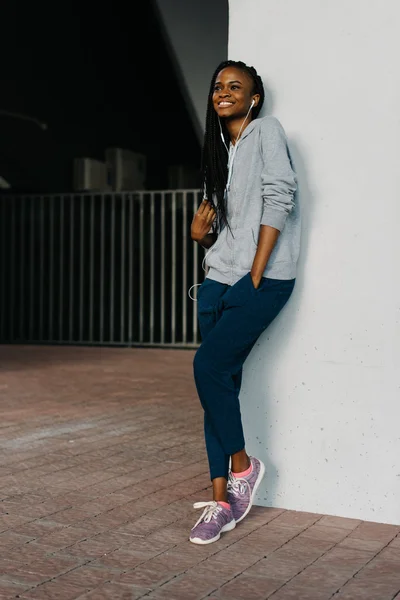 Fashion, technology and people concept - pretty smiling girl listen to music in headphones against white wall