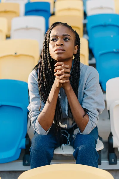 Unhappy and frustrated african american woman sitting with her chin resting on hands, looking away