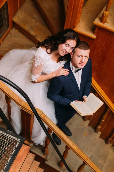 Elegant newlywed couple posing on stairs at old library. The view from the top