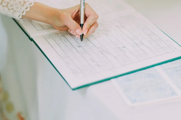 Bride signing marriage license or wedding contract, close up female hand with pen