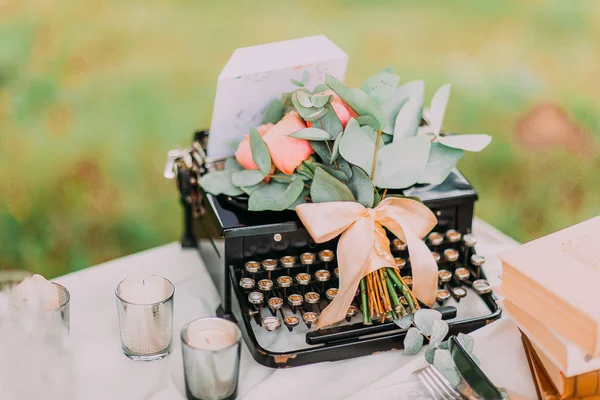 Vintage black typewriter and flowers on white table, outdoors