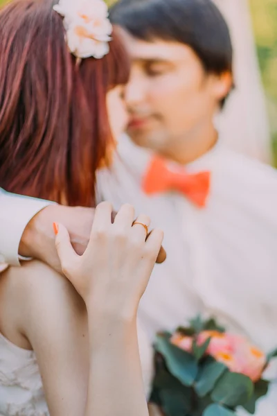 Pretty red-head bride looking at handsome groom holding his hand on her shoulder , close-up