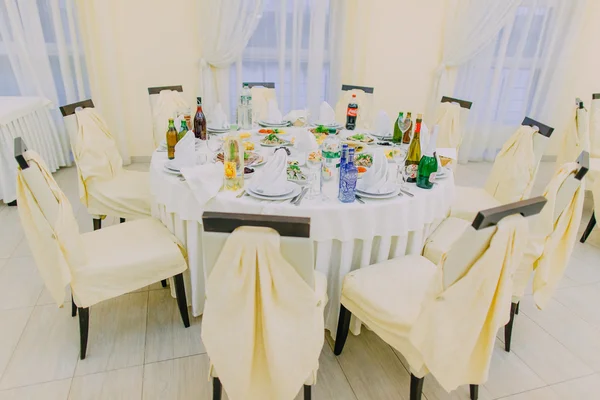 Luxury restaurant table set with served food, drinks and decorated chairs for event