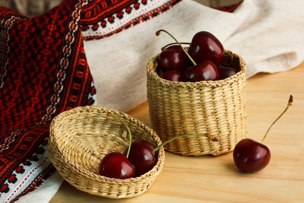 Cherries in wicker bowl on a wooden table with a linen cloth in