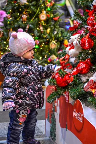 MOSCOW, RUSSIA - November 17,2013: Little girl near a Christmas tree beautiful Coca-Cola in GUM on November 17,2013 in MOSCOW, RUSSIA