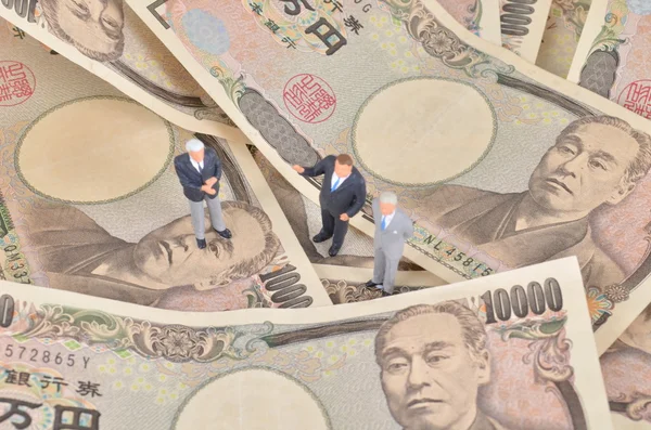 Miniature businessman standing on japan dollar.