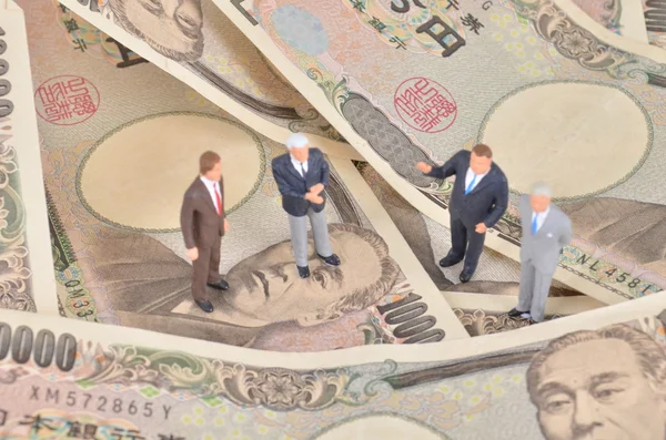 miniature businessman standing on japan dollar.