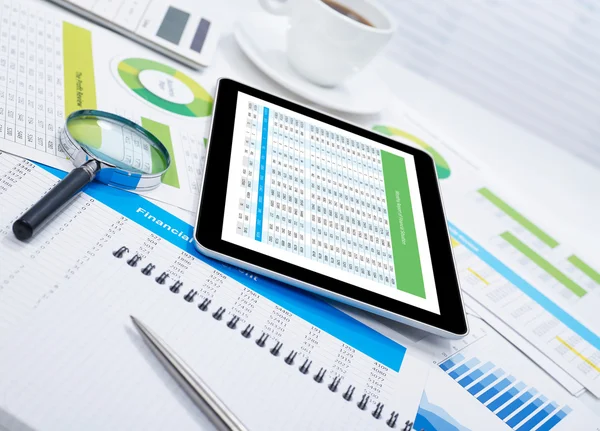 Tablet on desk and financial papers