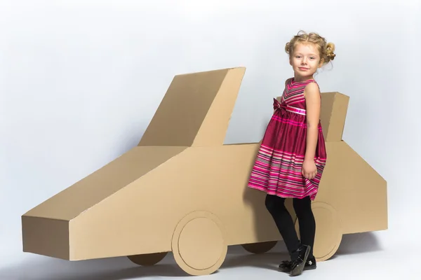 Smiling happy girl near cardboard car. full length female portrait