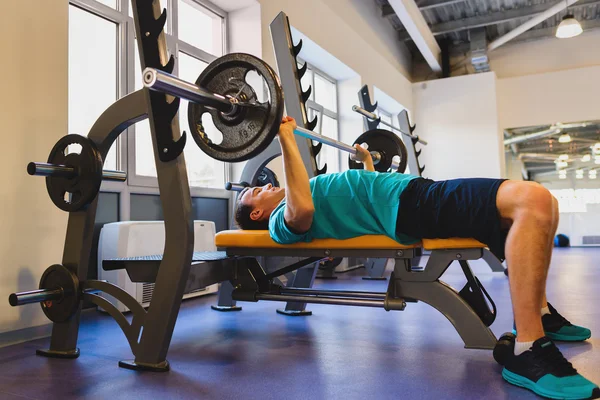 Young Man In Gym Exercising Chest On The Bench Press with barbell