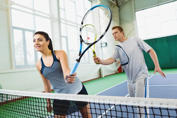 Low angle view of determined young man and woman playing tennis indoor