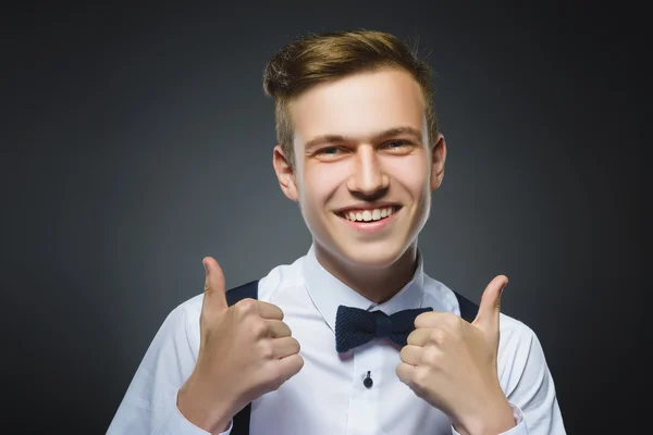 Closeup portrait successful happy boy show thumb up isolated grey background. Positive human emotion.