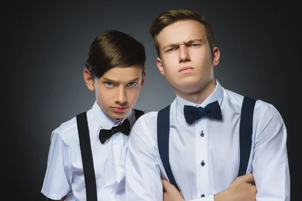Portrait of two angry boys isolated on gray background. Negative human emotion, facial expression. Closeup