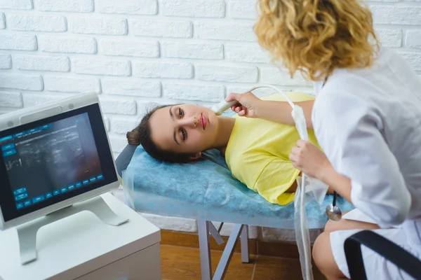 Female doctor examines girls lymph node with ultrasound in medical center