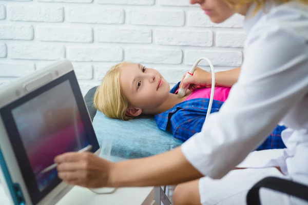 Female doctor examines girls thyroid with ultrasound in medical center