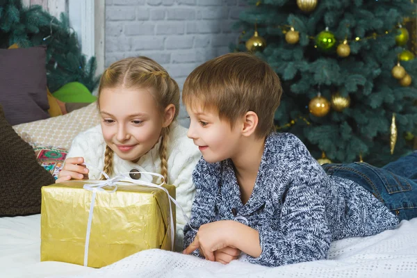 Happy boy and girl lying on bed. Next to gifts. Waiting for Christmas. Celebration. New Year.