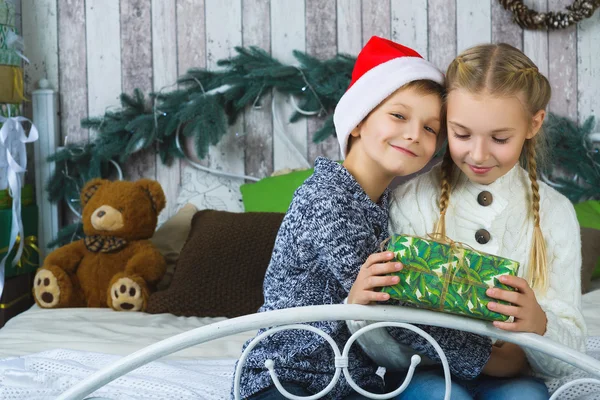 Happy children sitting on bed and holding gifts. Waiting for Christmas. Celebration. New Year.