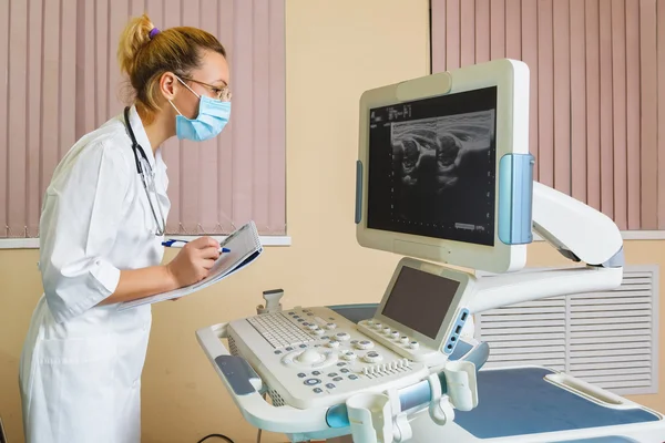 Female doctor looking at a monitor device for ultrasound diagnostics