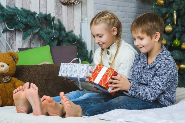 Happy children sitting on bed and holding gifts. Waiting for Christmas. Celebration. New Year.