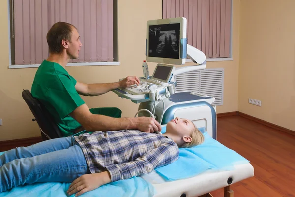 Girl getting ultrasound of a thyroid from doctor