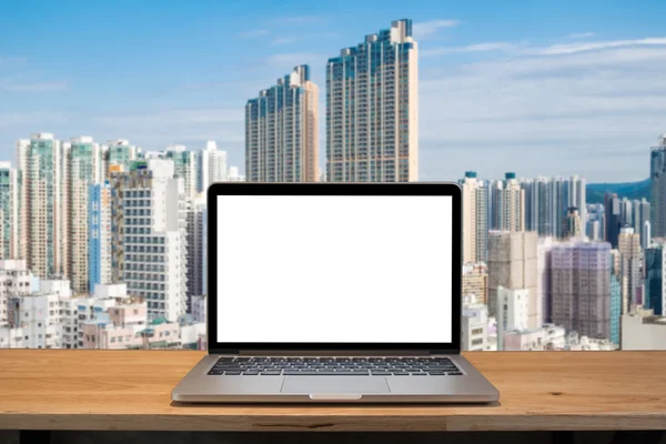Laptop with blank screen on table. hong kong building background