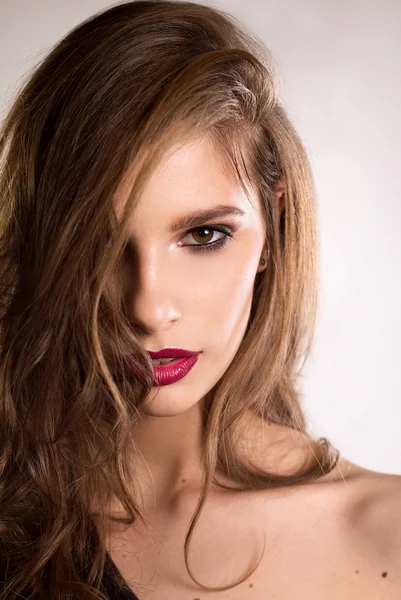 Portrait of brunette woman on a light background in black clothes with collected hair and red lipstick