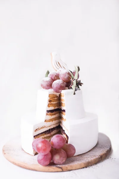 Cut cake souffle on a white background with white decor and grapes