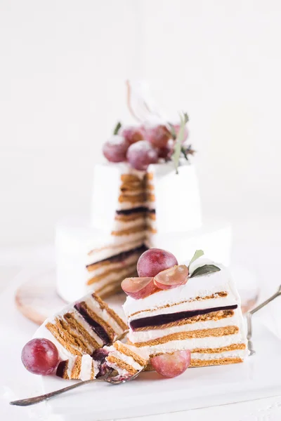 Cut cake souffle on a white background with white decor and grapes