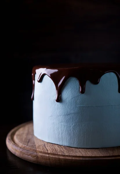 Blue cake decorated with  chocolate frosting on a dark wooden background