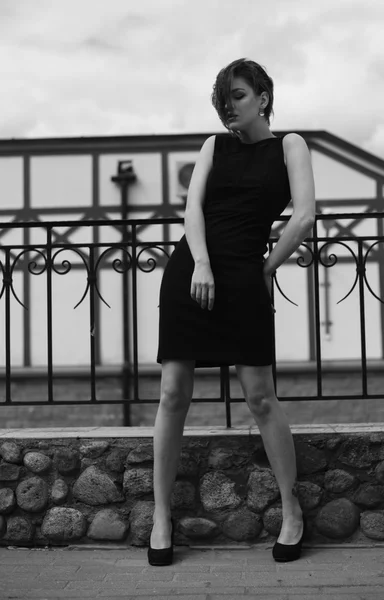 Vogue model in the black dress outdoor near fence