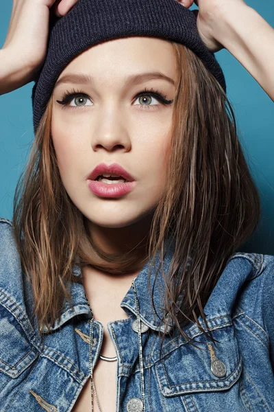 Closeup studio shot of pretty hipster teenage girl with beanie hat wearing jeans jacket looking at camera posing.