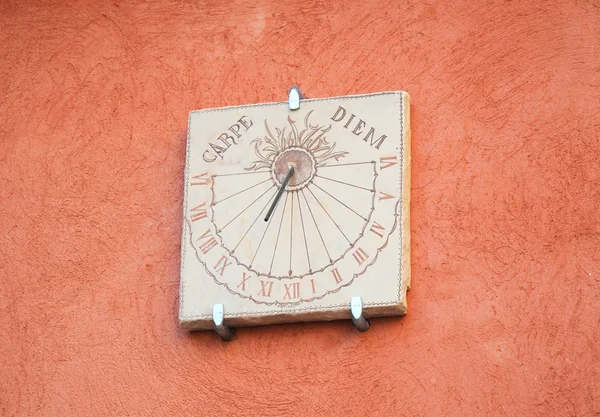 Sundial reminding of carpe diem on red wall