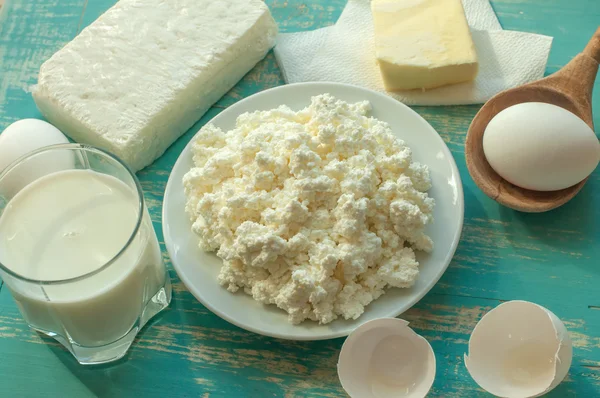 Diary products - milk, cottage cheese, butter and eggs - on a wooden surface