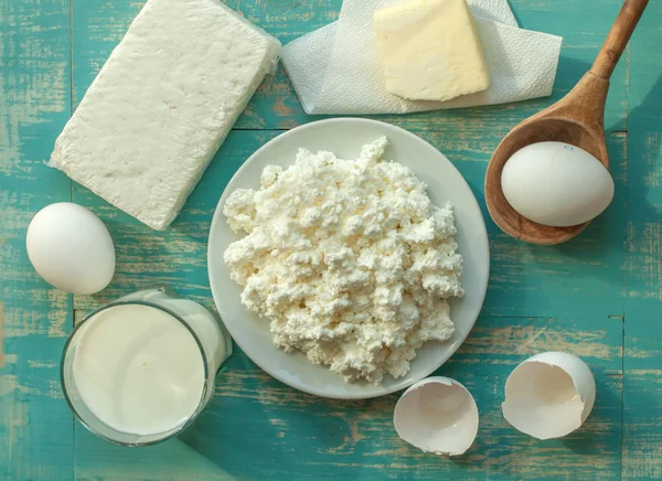Diary products - milk, cottage cheese, butter and eggs - on a wooden surface