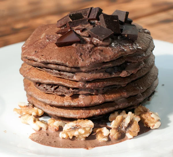 A stack of chocolate pancakes decorated with liquid chocolate sauce