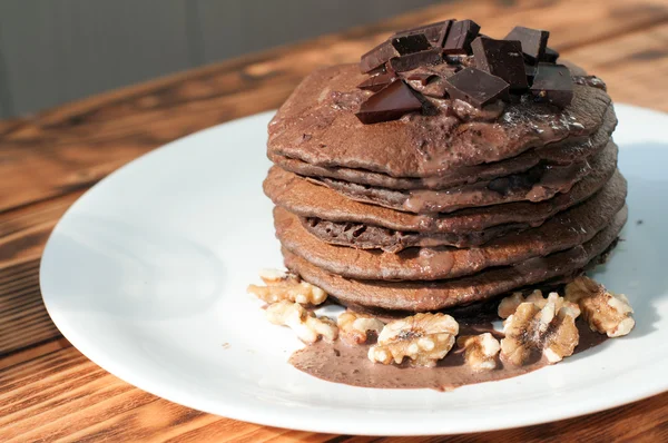 A stack of chocolate pancakes decorated with liquid chocolate sauce