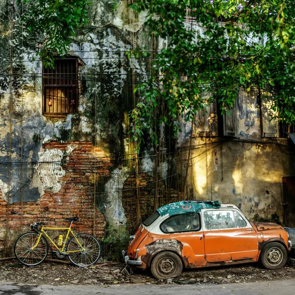 Rusty car and bicycle near abandoned building