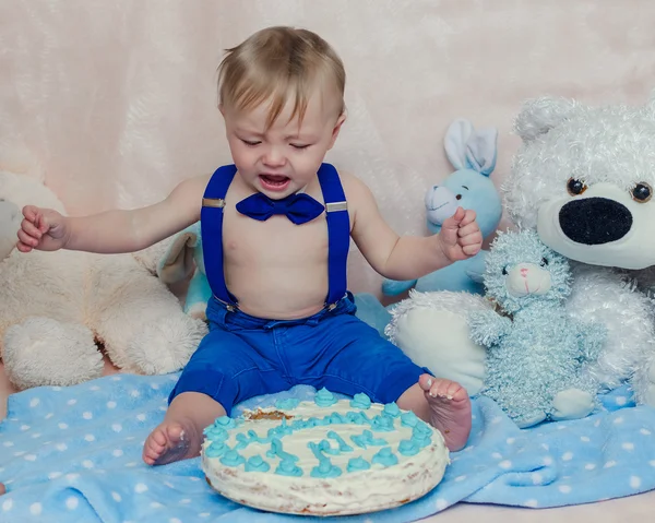 Baby boy crying while eating his birthday party cake