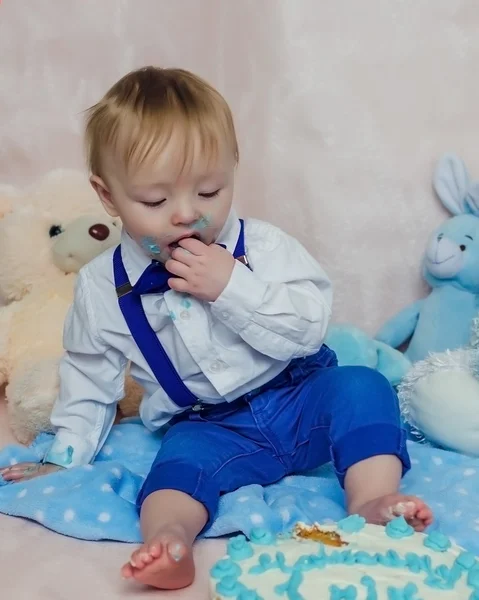 Happy baby boy eating cake for his first birthday party