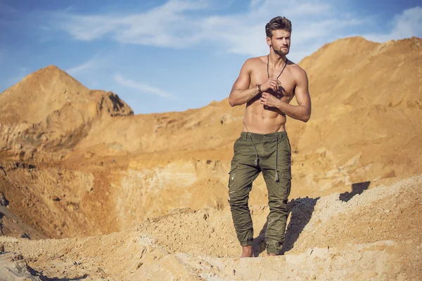 Handsome well-built man walking in the desert