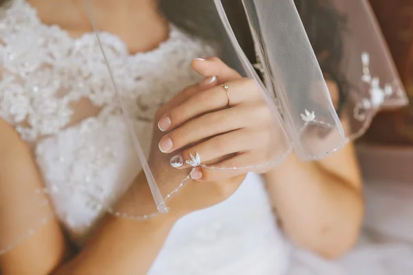 Hands of the bride and white bride dress