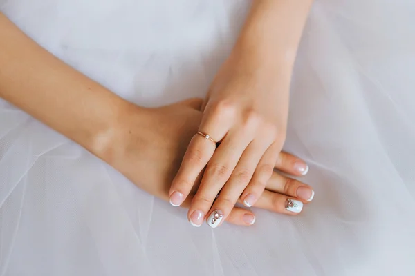 Hands of the bride and white bride dress