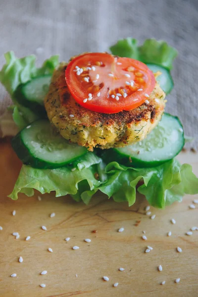 Vegetarian Sandwich  with chickpeas lentil cutlet, cucumber, fresh lettuce, and tomato. Sprinkle with sesame seeds. Sandwich on the wooden table.