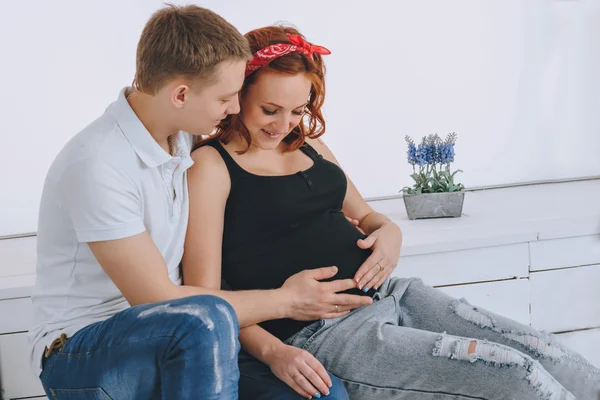 Pregnancy. Man and woman looking at pregnant belly. The husband keeps his hand on the belly wife. Future parents. Waiting for a miracle