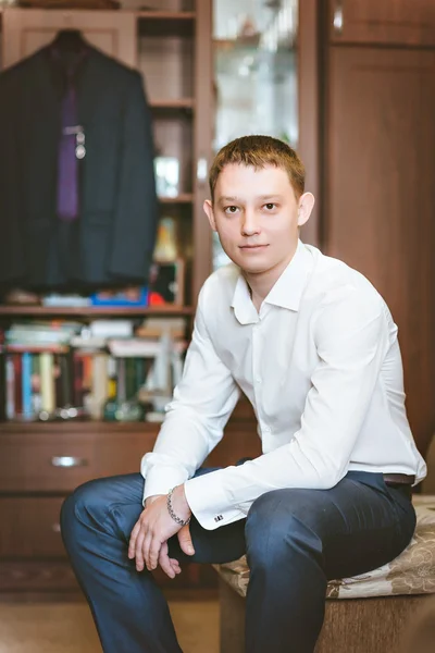 Portrait young man in white shirt. Sitting on the couch, background suit.