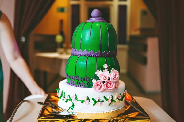 Green purple wedding cake with pink flowers, in an Oriental style.