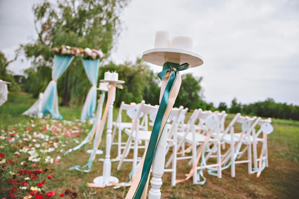Beautiful wedding set up. wedding decor on the lawn, wedding arch, chairs with ribbons. turquoise, purple and white. The rose petals on the ground. Wedding ceremony