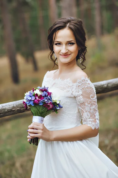 Portrait of bride with bouquet. Young beautiful woman in the forest. Lilac, purple, white, serenity wedding bouquet
