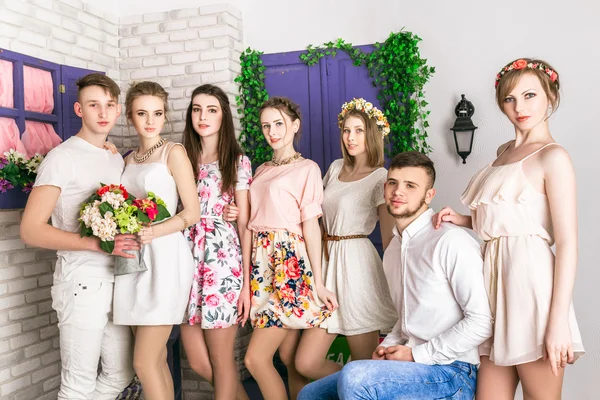 Company of young beautiful people posing in spring studio