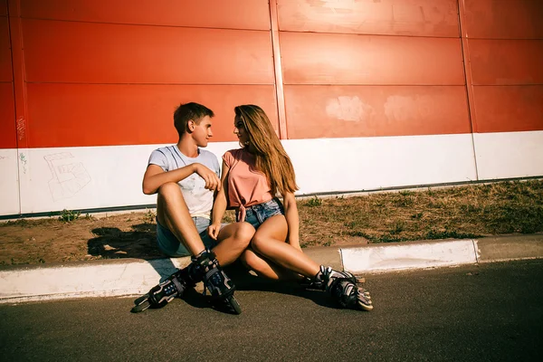 Couple sitting on the curb on a red wall